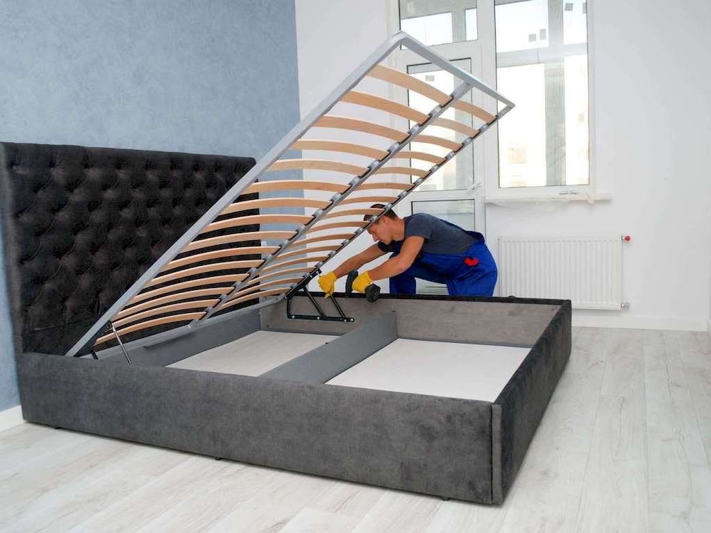 Egy bútorasztalos ágy összeszerelés közben Budapesten